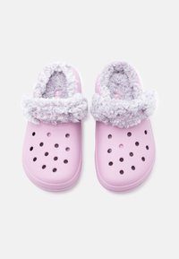 Un paio di zoccoli rosa chiaro con fori di ventilazione rotondi e una morbida e soffice fodera bianca intorno alla caviglia.