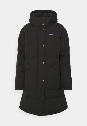 Musta pitkä toppatakki hupulla, edessä nepparikiinnitys, sivutaskut ja Patagonia-logo rinnassa.