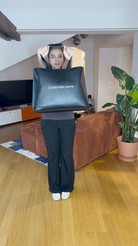 Stor sort tote bag med præget "Calvin Klein Jeans" logo. Har robuste håndtag og en glat, tekstureret overflade.
