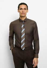 Braunes Hemd mit Muster und langen Ärmeln, kombiniert mit einer diagonalen gestreiften Krawatte in Blau- und Brauntönen, getragen zu braunen Hosen.