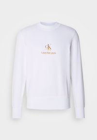 Sweat-shirt blanc à manches longues et col rond avec petit logo doré et beige « cK Calvin Klein Jeans » centré sur la poitrine.