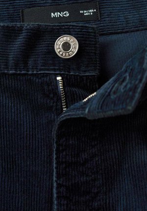 Námornícky kordurové nohavice s vertikálnymi pruhmi, so zlatou gombíkovou a zipsovou popruhou; štítok označuje veľkosť EU 36 / USA 4 / MEX 3.