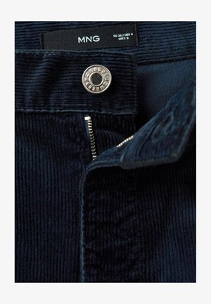 Námornícky kordurové nohavice s vertikálnymi pruhmi, so zlatou gombíkovou a zipsovou popruhou; štítok označuje veľkosť EU 36 / USA 4 / MEX 3.