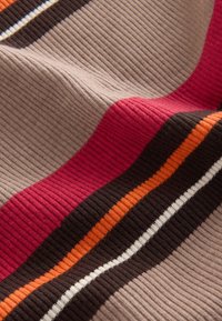 Ribaina auduma, kurā mainās horizontālās svītras sarkanā, brūnā, oranžā, krēmkrāsā un bēšā krāsā. Mīksta tekstūra ar nelielu stiepjamību.