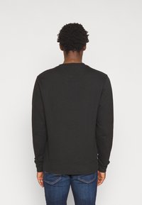 Svart sweatshirt med rund hals, ribbade ärmslut och nederkant. Tillverkad av bomullsmaterial, med en enfärgad ytfinish utan mönster eller detaljer.