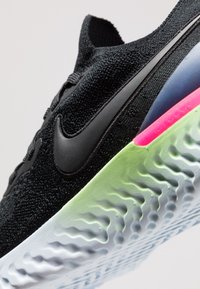Černé pletené sportovní boty s texturovaným svrškem, černými akcenty a vícebarevnou podrážkou s zelenými, modrými a růžovými detaily.