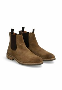 Bottines Chelsea en cuir suédé marron avec des panneaux élastiques sur les côtés, des languettes de tirage et une semelle en bois plate. Bout arrondi et texture douce pour le confort.