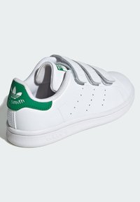 Baltas kedas ar zaļiem papēžiem un mēles akcentiem, kas aprīkoti ar trim pelēkiem āķa un cilpas siksniņām, perforētu dizainu un teksturētu zoli.