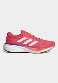 Zapatilla deportiva con parte superior de malla rosa, logotipo de tres rayas blancas y tejido texturizado. Presenta una suela blanca acolchada con un acento de degradado azul.