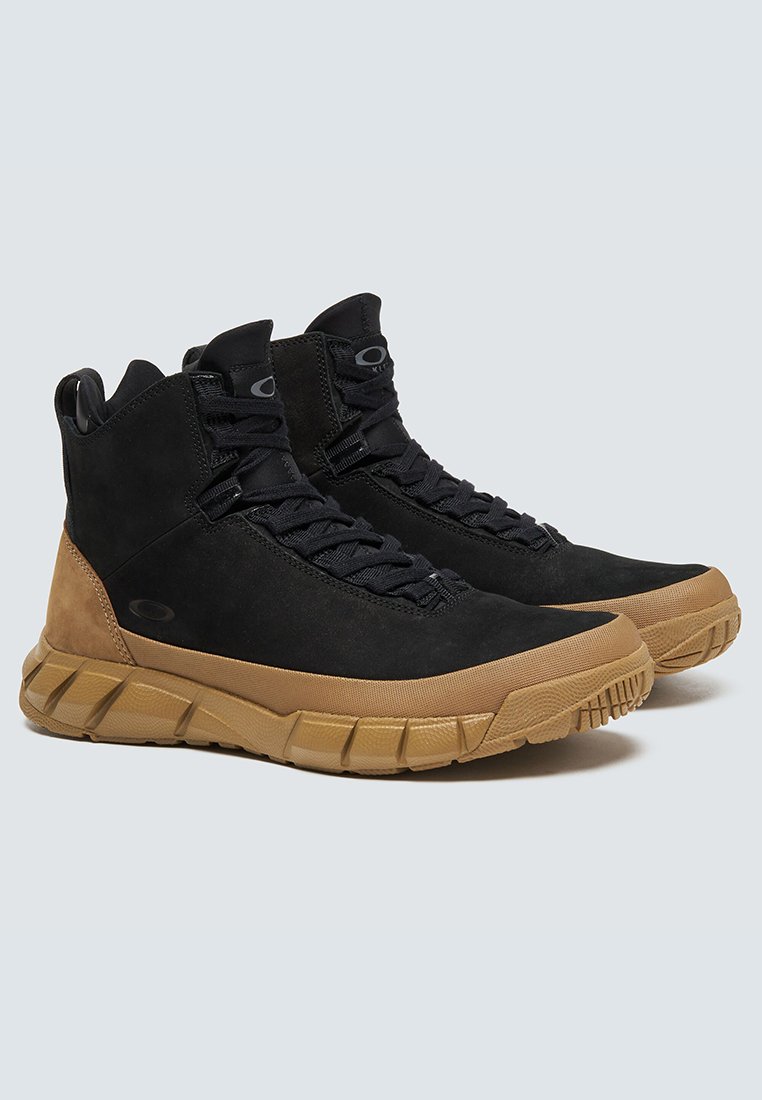 Botas altas de ante negro con una suela de goma texturizada marrón. Diseño de cordones con un collarín acolchado y un logotipo destacado en el costado.