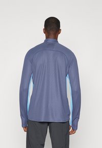 T-shirt de sport à manches longues en bleu foncé avec des accents bleu clair, présentant un col haut et un tissu texturé pour la respirabilité.