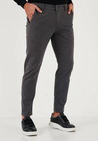 Sivi bombažni chinos hlače s slim fit krojem, ki vključujejo sprednje žepe in zadrgo. Ujemite jih s črnimi supergami za sproščen videz.