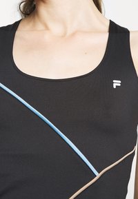 Svart atletisk linne med kurviga ljusblå och beige accenter. Tyget är mjukt med en figurnära design. Logotypen visas på bröstet.