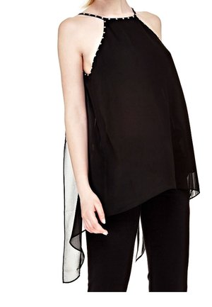 Haut noir sans manches à col halter avec un col orné de perles et un dos asymétrique en tissu transparent, porté avec un pantalon noir.