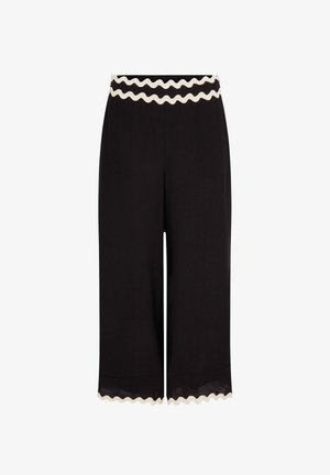 Pantalon large noir raccourci avec bordure blanche festonnée à la taille et à l'ourlet.