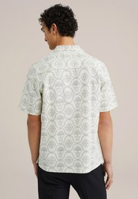 Cămașă cu mâneci scurte dintr-un material crem deschis, având un model floral repetitiv în nuanțe de gri. Design cu guler și o croială confortabilă.