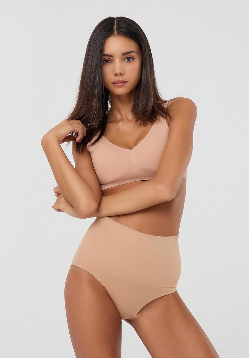Set beige in due pezzi composto da un reggiseno a V e da slip a vita alta, realizzato in tessuto morbido con design senza cuciture e senza hardware visibile.