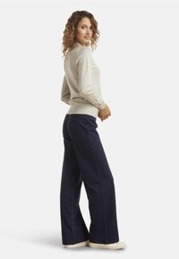 Light gray long-sleeve sweater paired with navy wide-leg pants, featuring a smooth texture and relaxed fit, complemented by white shoes.