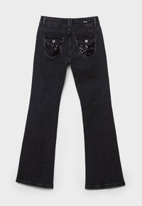 Schwarze Jeans mit ausgestelltem Bein aus Denim, mit zwei Gesäßtaschen, die mit Paillettenakzenten und Metallbeschlägen versehen sind, von hinten gezeigt.