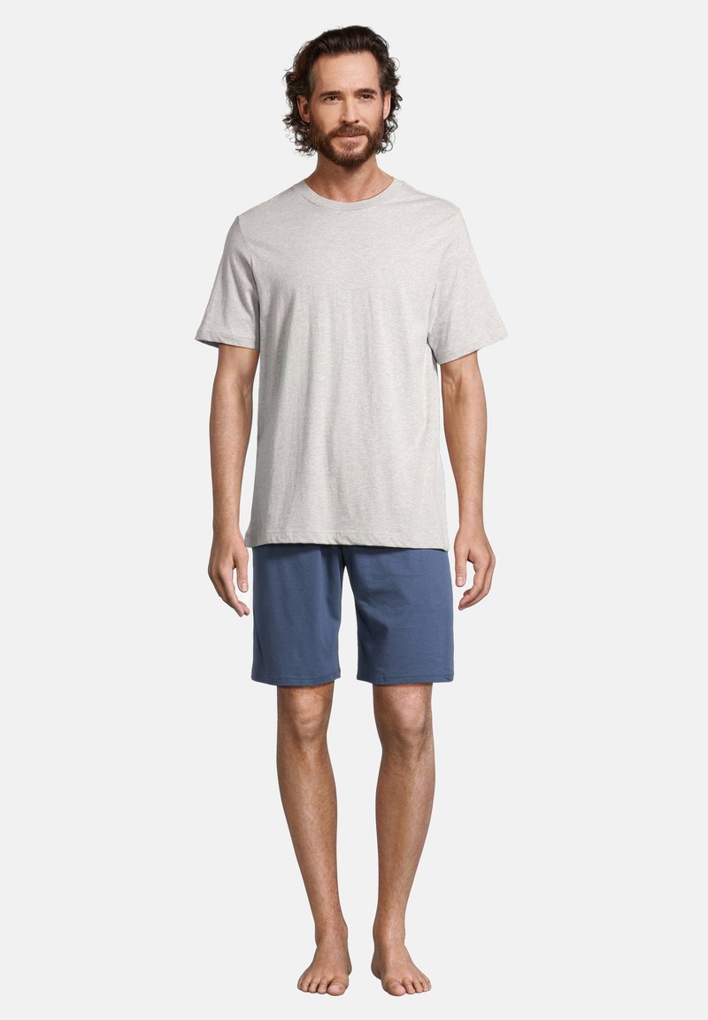 Ljusgrå bomullströja med korta ärmar i en avslappnad stil, kombinerad med blå shorts. Ingen synlig mönster eller dekoren. Barfota.