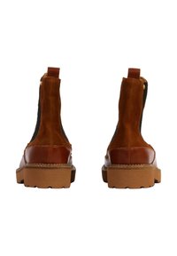Botas de tobillo de ante marrón con un ribete de cuero suave, paneles laterales elásticos y una suela de goma gruesa con un patrón texturizado.