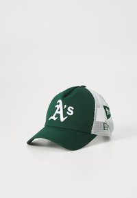 Vihreä ja valkoinen verkkomallinen baseball-lakki, jossa on valkoisesti brodeerattu "A:n" logo ja lisäpatchit sivupaneelissa, valkoista taustaa vasten.