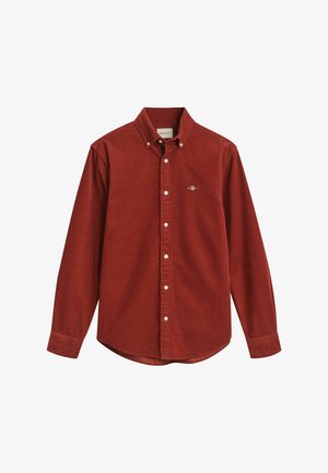 Red corduroy button-up shirt with long sleeves and a pointed collar. Features a small embroidered logo on the chest and a curved hem.