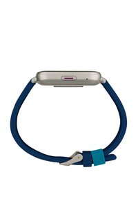 Montre intelligente argentée avec un bracelet en silicone bleu étroit. Présente une boucle métallique et un accent violet près du port de recharge.
