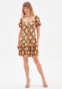 Robe courte à motifs en orange, vert et crème avec des manches bouffantes, un col carré et un ourlet à volants en étages. Détails de boutons sur le devant.
