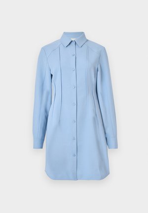 Lyseblå skjortekjole med krave, lange ærmer, lodrette syninger og en let buet kant. Fremstillet af en blød, tekstureret stof.