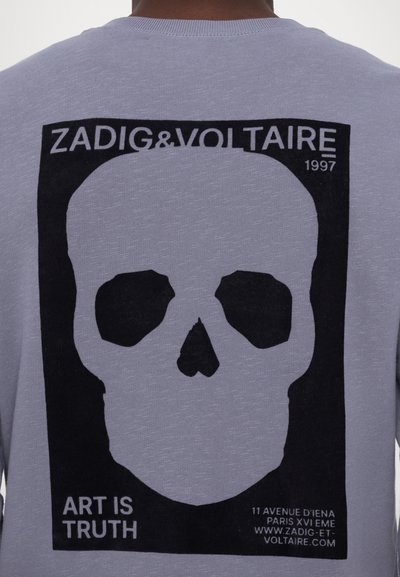 T-shirt gris avec un grand graphique de crâne noir au dos, accompagné du texte "ZADIG&VOLTAIRE 1997" et "L'ART EST LA VÉRITÉ" en dessous.