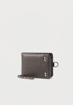 Portofel negru din piele cu nituri argintii și lanț metalic atașat pe un fundal simplu, deschis la culoare.