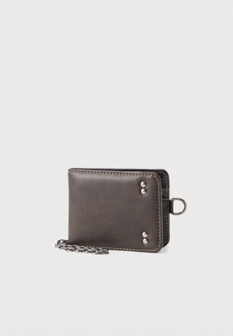 Μαύρο δερμάτινο πορτοφόλι με ασημένιες πριτσίνια και προσαρτημένη μεταλλική αλυσίδα σε απλό φωτεινό φόντο.