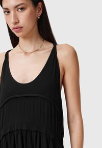 Vestido negro sin mangas con escote redondeado, diseño en capas y textura suave. Acabado con tirantes delgados y una silueta fluida.