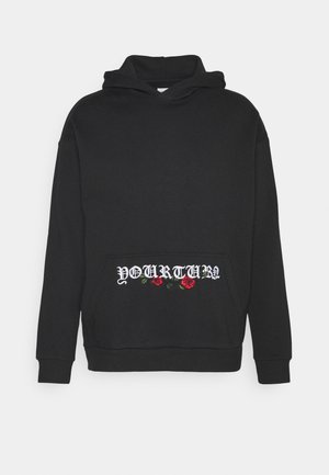 Felpa nera in cotone, con tasca a canguro frontale. Testo ricamato "IL TUO TURNO" e rose rosse nella zona della tasca.