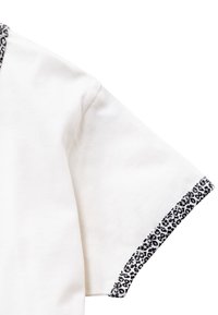 Camiseta blanca de manga corta con ribete de estampado de leopardo negro en los dobladillos de las mangas y el cuello. Textura de algodón suave.