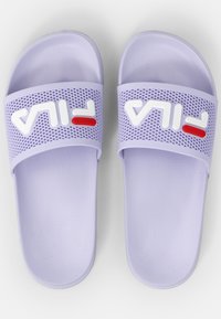 Vaaleanvioletit liukusandaalit, joissa on tekstiiliraidoitus ja valkoinen FILA-logo punaisella korostuksella, valmistettu pehmeästä kumimateriaalista.