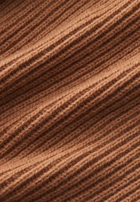 Tissu en tricot côtelé marron avec une apparence texturée, présentant des lignes horizontales en relief et une sensation douce et chaleureuse.
