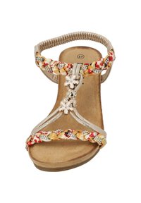 Beige Sandale mit geflochtenen, mehrfarbigen Riemen, floralen Akzenten und Strassdetails. Flache Sohle mit gepolstertem Fußbett. Größe 37.