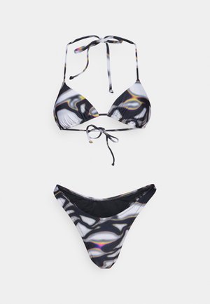Μαύρο και άσπρο σετ μπικίνι με τριγωνικό τοπ με ρυθμιζόμενους κορδόνες και υφασμάτινη κάτω μέρος, που παρουσιάζει ένα κυματιστό, αφηρημένο μοτίβο.