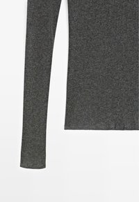 Maglia grigia a maniche lunghe con costo a costine, realizzata in un tessuto stretch testurizzato, con maniche aderenti e orlo dritto.