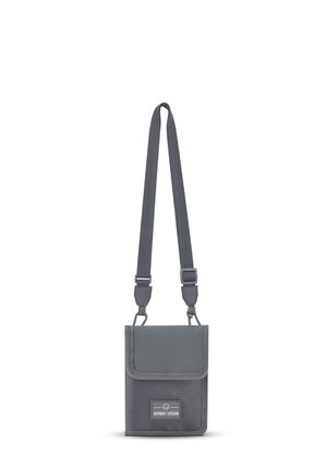 Gray crossbody bag made of durable fabric, featuring a flap closure, adjustable strap, and a front label with brand name.