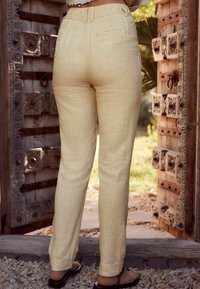 Helle gelbe Leinenhosen mit lockerem Schnitt, ausgestattet mit einem Bund und Rücktaschendetails. Flat-Front mit geraden Beinen.