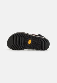 Czarna gumowa podeszwa buta z diamentowym wzorem bieżnika oraz żółtym logo Vibram, z gładką, wykończoną górną częścią.
