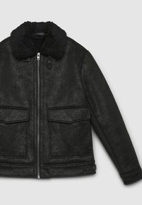 Giacca nera in pelle sintetica con finitura texturizzata, colletto in pelliccia sintetica, chiusura frontale con zip e due ampie tasche a toppa.