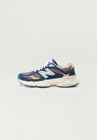 Navy and beige sneaker with mesh and suede materials, white accents, thick sole, and laces; features a prominent "N" logo on the side.