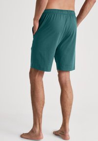 Teal katoenen shorts met een elastische tailleband, voorzien van zijzakken en een rechte pasvorm. De stof heeft een zachte textuur.