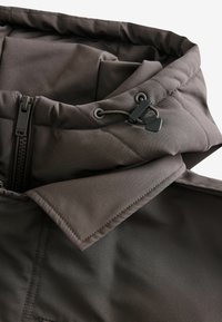 Dunkelbraune, isolierte Jacke mit hohem Kragen, ausgestattet mit einem Frontreißverschluss, verstellbarem Kordelzug und glattem, strukturiertem Stoff.