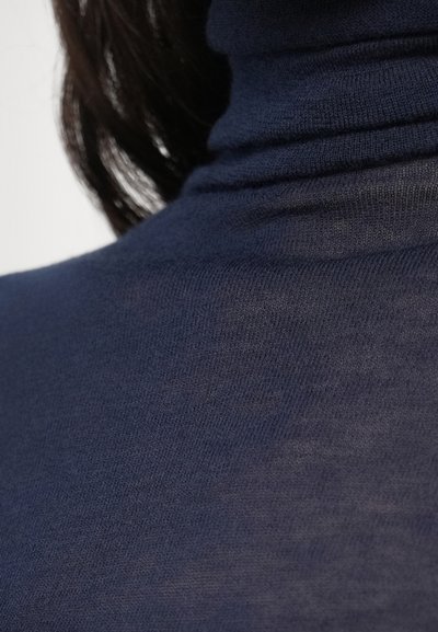 Meresinine kaelusega džemper, pehme kootud tekstuur, keha järgiv lõige koos soonikkoes kaeluse detailidega. Ilma nähtavate mustrite või aksentideta.