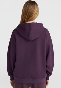 Felpa viola con una texture morbida, vestibilità rilassata e un grande cappuccio. Presenta spalle scese e polsini a coste sulle maniche e sull'orlo.